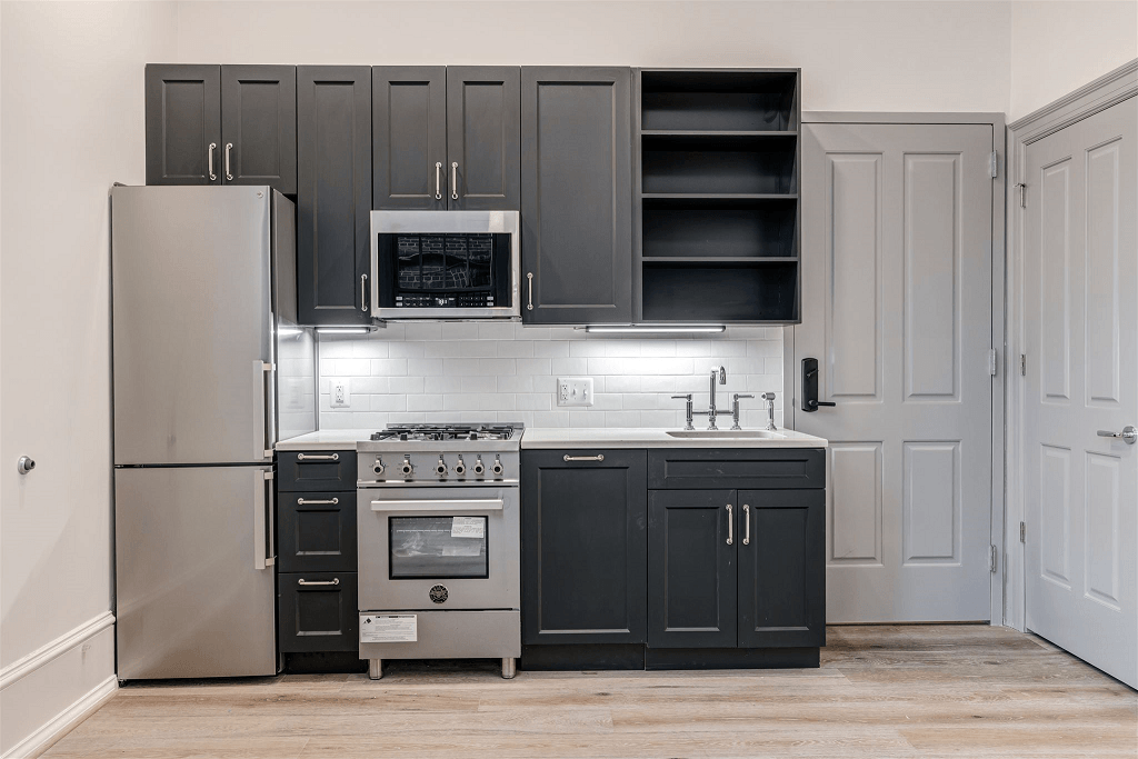 a kitchen with black cabinets and stainless steel appliances and a refrigerator